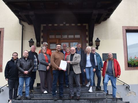 Bürgermeister Matthias Horlacher (vorne links) nahm in im Beisein von Mitgliedern der Steuerungsgruppe und des Gemeindevorstands von Landrat Frank Matiaske (vorne rechts) entgegen.